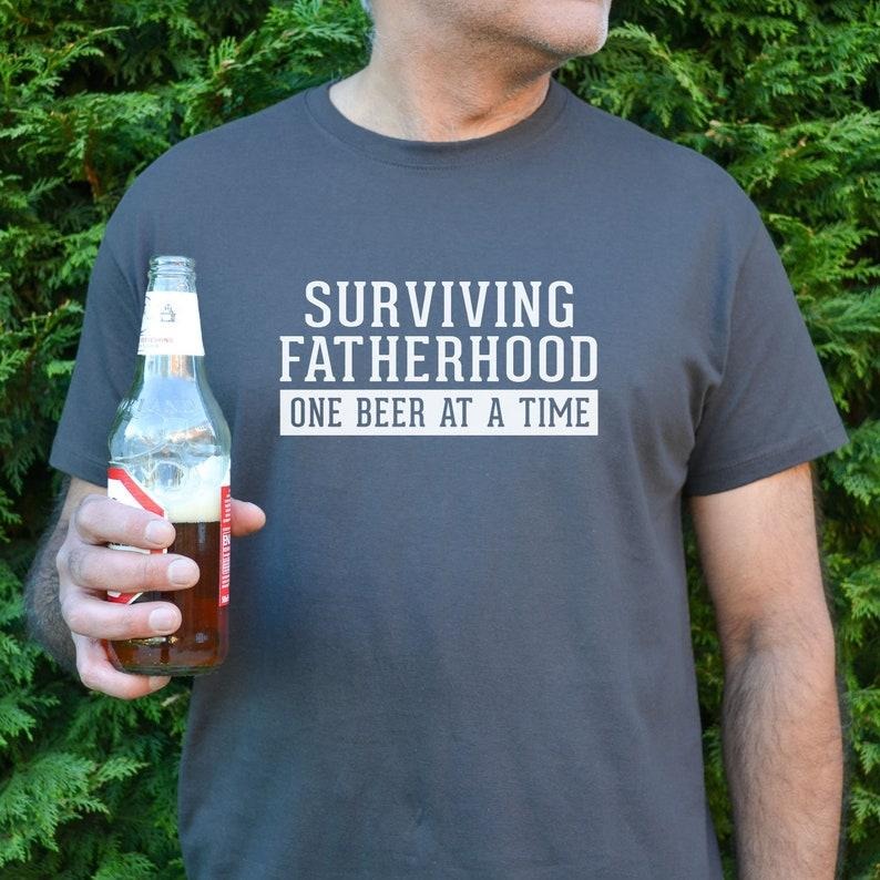 Surviving Fatherhood Dad Beer - Adult & Kids T-Shirts, Sweatshirts & Hoodies apparel design preview 1